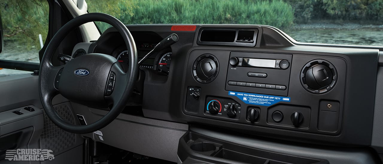vehicle dashboard showing steering wheel, speedometer, air conditioning controls, vents and radio
